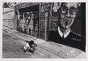 Untitled (Boy with tricycle, on street with murals) by Oweena Camille Fogarty